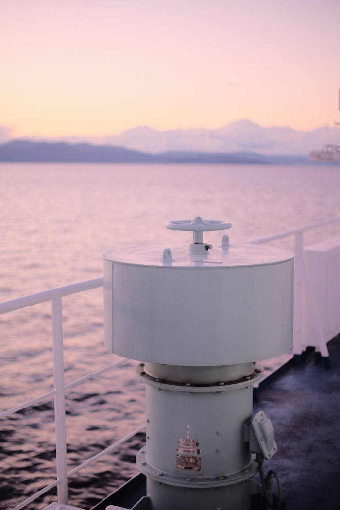 A serene view from a ships deck during sunset, overlooking a calm sea.